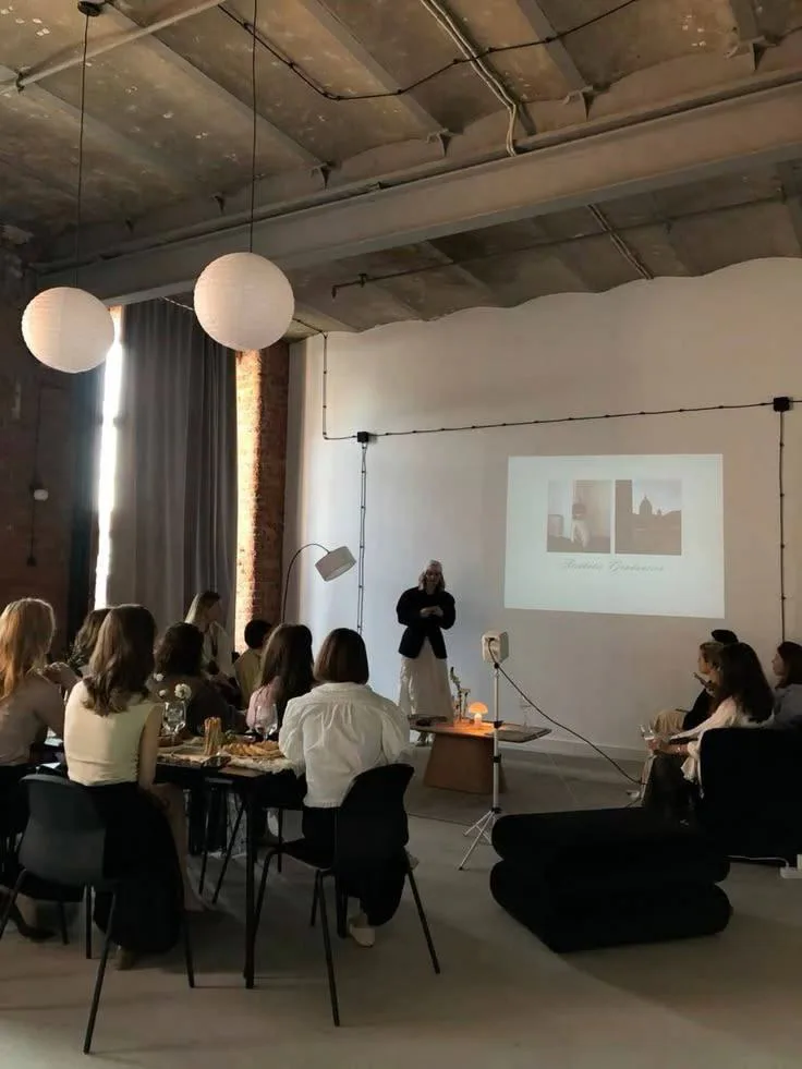 Equipo sentado a la mesa escuchando una presentación proyectada en un loft